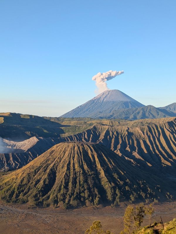 Mount Semeru erupting behind Mount Bromo as seen from King Kong Hill sunrise viewpoint in East Java