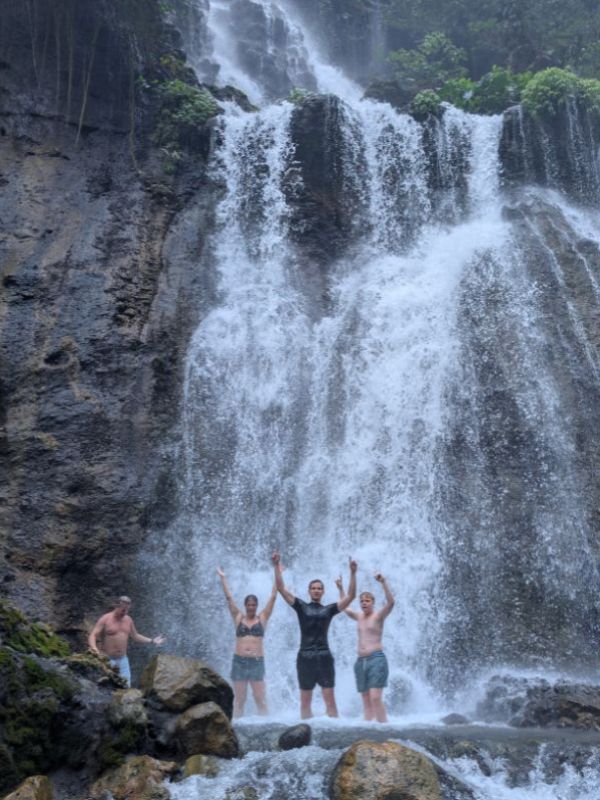 Family standing beneath Tumpak Sewu Waterfall during a private East Java tour